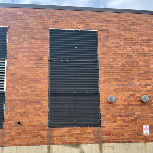 Air intake screen installed on exterior wall louver of a commercial building